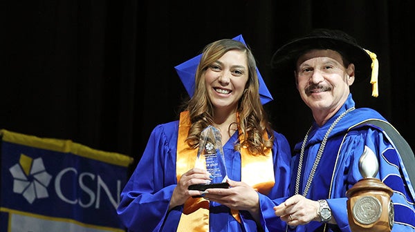 Graduate receiving the Commencement Student Speaker Award on stage during commencement ceremony.