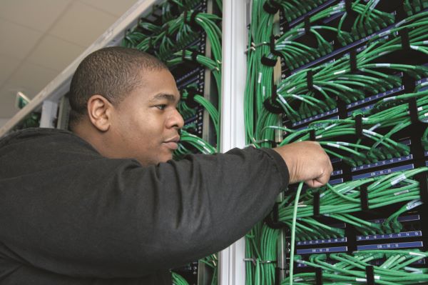 man moving wires on a server rack